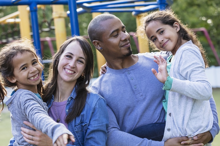 Mixed race family with two girls have fun on playground